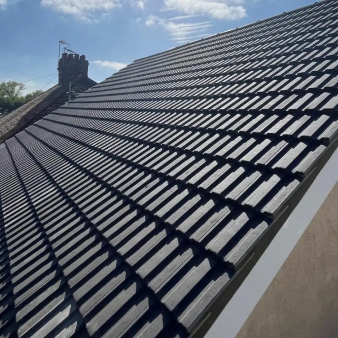 Close-up of a newly installed, durable deep charcoal concrete tiled pitched roof adhering to British Standards. By Norfolk Exterior Solutions